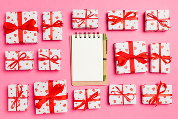 Fototapeta na wymiar Top view of notebook, white gift boxes with red hearts on colorful background. Valentine's Day concept