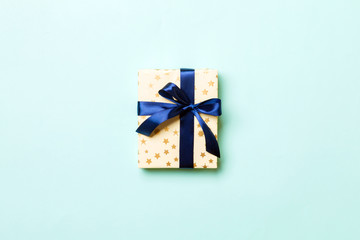 Top view woman hands holding Christmas present box with blue bow on blue background with copy space