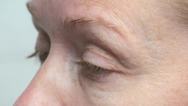 Sleepy woman claps eyelashes closeup.