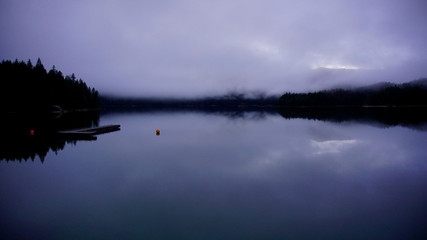 Eibsea at Zugspitze in the Alps. Tourism spot. Nice hiking trail around the lake. Fir trees, rock fragments, stones. Mountains in background. Insta spot. After sunset. Reflections on water.