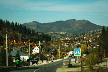 Village in the mountains. A beautiful sunny landscape with mountains. Blue sky, grass and forest. Background or wallpaper.