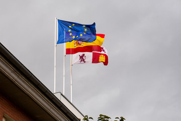 Flags of Europe, Spain and castile and lion waving in the wind over a cloudy sky.