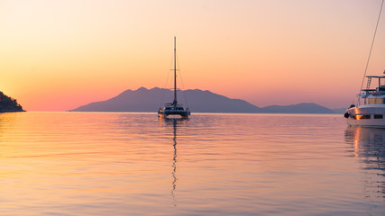 Scenic beautiful sunrise with a view on a boat at the marine of Epidaurus Island, Peloponnese, Saronic Gulf, Greece. 
