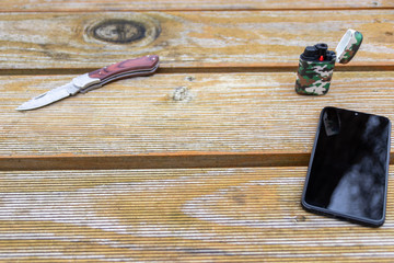Outdoor-Equipment mit Smartphone in schwarz, Taschenmesser mit scharfer Klinge und camouflage...
