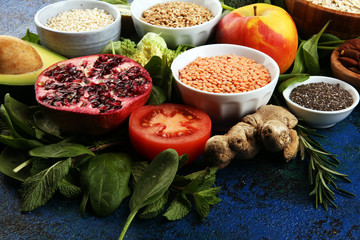 Healthy food clean eating selection: fruit, vegetable, seeds, superfood, cereals, leaf vegetable on rustic background