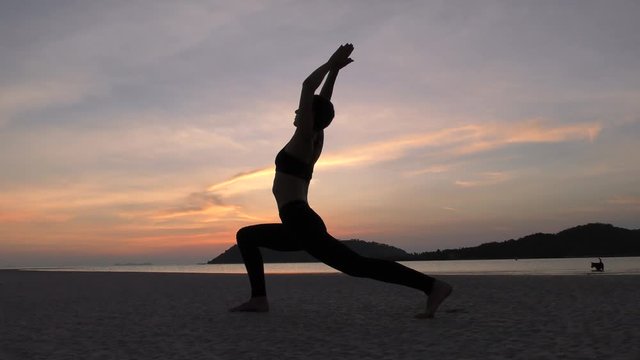 Woman Practicing Yoga on the Beach at Sunset. Female Doing Exersice at the Sea