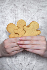 Gingerbread men in woman hand against the white knitted sweater