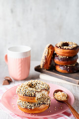 Stack of donuts with chocolate glaze and waffle crumbs on a pink plate with a pink striped napkin,...