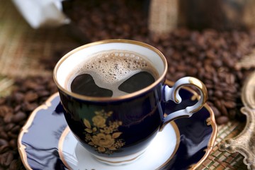 Package with coffee in grains cup with coffee with foam and coffee grains on the table
