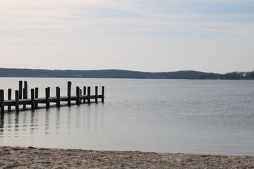 Fototapeta na wymiar Old weathered wooden dock on a sandy coastal