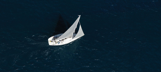 Aerial drone ultra wide photo of beautiful sailboat cruising in Aegean deep blue sea