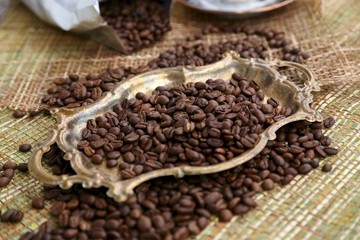 Vintage tray with large grains of special roasting coffee and bag packing for coffee on the table