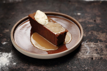 Chocolate cake with caramel sauce and whipped cream. Food, ready dish on a dark background. Suggestion of serving the dish.