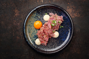 Beef sirloin tartare with egg yolk. Food, ready dish on a dark background. Suggestion of serving the dish.