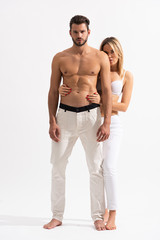 sensual woman hugging shirtless torso of man on white