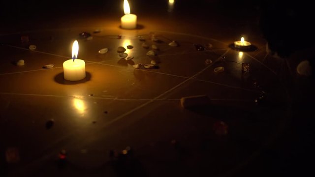 shells and stones, white candles burn in the pentagram on a wooden floor. Black cat. Magical ritual with occult, evil and esoteric symbols. Halloween Scary Rite
