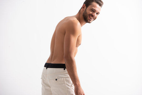 cheerful shirtless man in white jeans, isolated on white