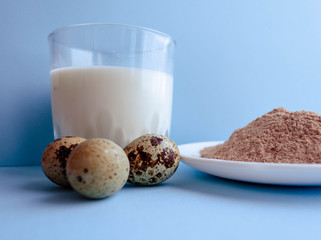 Natural organic Ingredients for making a cake, biscuit, pie, cookies, cacao flour, eggs  and milk on a blue background.  homemade  with copy space. Flat lay.