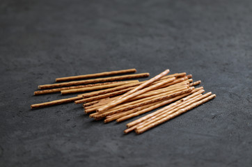 Cookie straws in a glass and scattered on a dark background