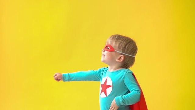 Superhero child against yellow background. Slow motion