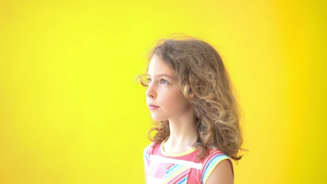 Beautiful teenager girl against yellow background. Slow motion