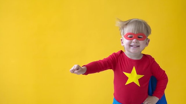 Superhero child against yellow background. Slow motion