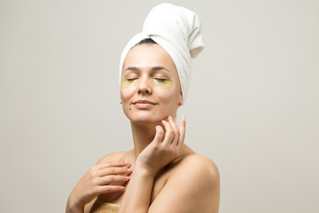 Young beautiful girl in a white towel on his head wears collagen gel patches under her eyes. Mask under eyes treatment face.