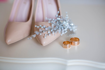 Close up of beige women shoes, two golden wedding rings, copy space. Wedding concept