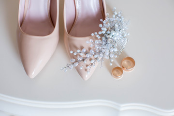 Close up of beige women shoes, two golden wedding rings, copy space. Wedding concept