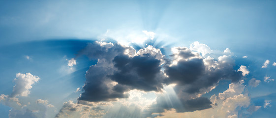 Rays of light with dramatic sky. Cumulus sunset dark clouds with sun setting down on dark background.Vivid orange and blue cloud sky.