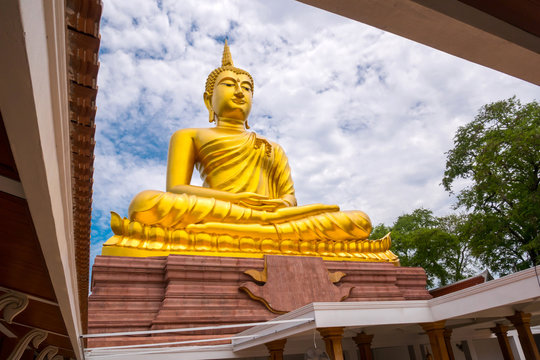 Beautiful  Big Golden Buddha statue against blue sky in Thailand temple,khueang nai District, Ubon Ratchathani province, Thailand.Amazing Buddha image with sunny sky clouds.