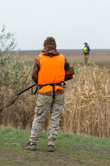 Hunting period, autumn season open. A hunter with a gun in his hands in hunting clothes in the autumn forest in search of a trophy.