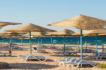 Beach umbrellas on the coastline of the sea at sunset.