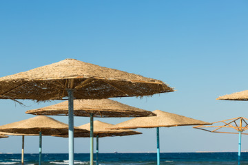 Beach umbrellas on the coastline of the sea at sunset.