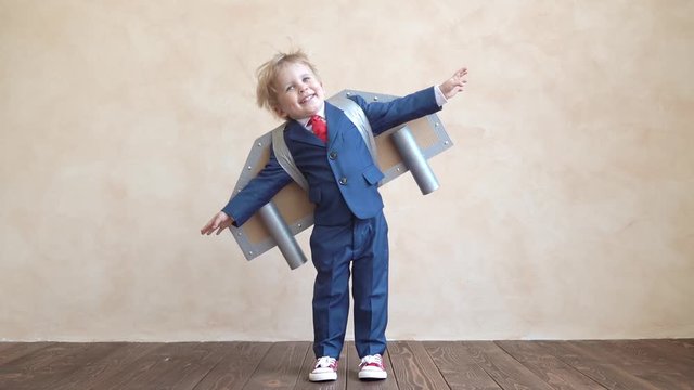 Happy child with toy paper wings. Slow motion