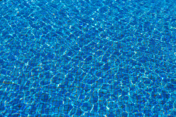 Surface of the pool, waves. The structure of blue tiles through the water.