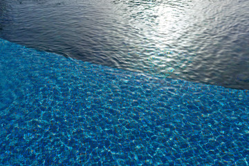 Surface of the pool, waves. The structure of blue tiles through the water.