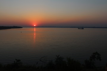 Obraz na płótnie Canvas The sun sets over the horizon above the river