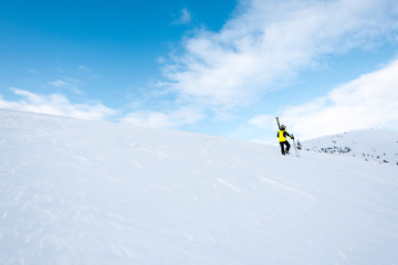 Naklejka na ściany i meble skier in helmet walking with ski sticks on slope in wintertime
