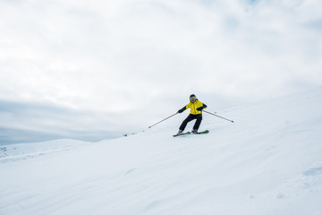 Naklejka na ściany i meble sportsman holding ski sticks and skiing on white slope
