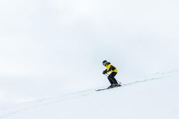 sportsman in helmet holding ski sticks while skiing in wintertime