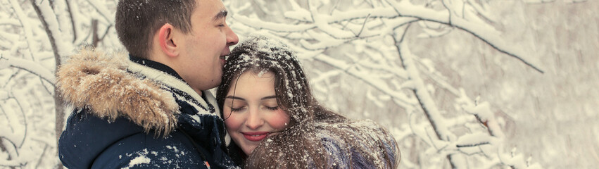 The guy and the girl have a rest in the winter woods. Husband and wife in the snow. Young couple walking in winter park	