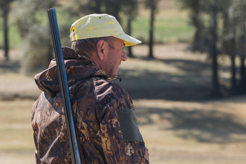 Silhouette of a hunter with a gun in the reeds against the sun, an ambush for ducks with dogs	