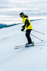 skier in helmet holding sticks and skiing on slope outside