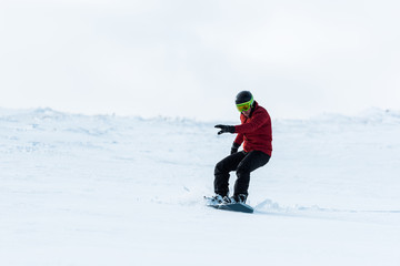 Fototapeta na wymiar athletic snowboarder in helmet riding on slope outside