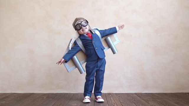 Happy child with toy paper wings. Slow motion
