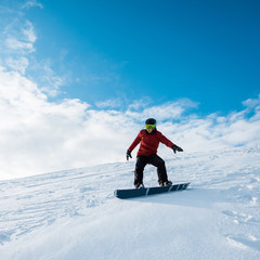 Fototapeta na wymiar snowboarder in helmet riding on slope against blue sky
