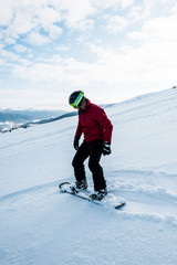 Fototapeta na wymiar snowboarder in helmet riding on slope with white snow in wintertime