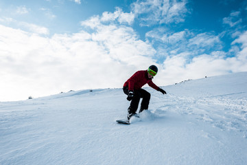 sportive snowboarder riding on slope with white snow in wintertime