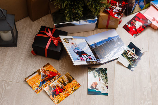 New Year celebrating. Photobook with photos of summer travel under the Christmas tree